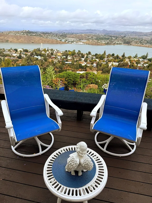 Restored swivel patio chairs with new blue slings and white powder-coated frames on a lake-view deck